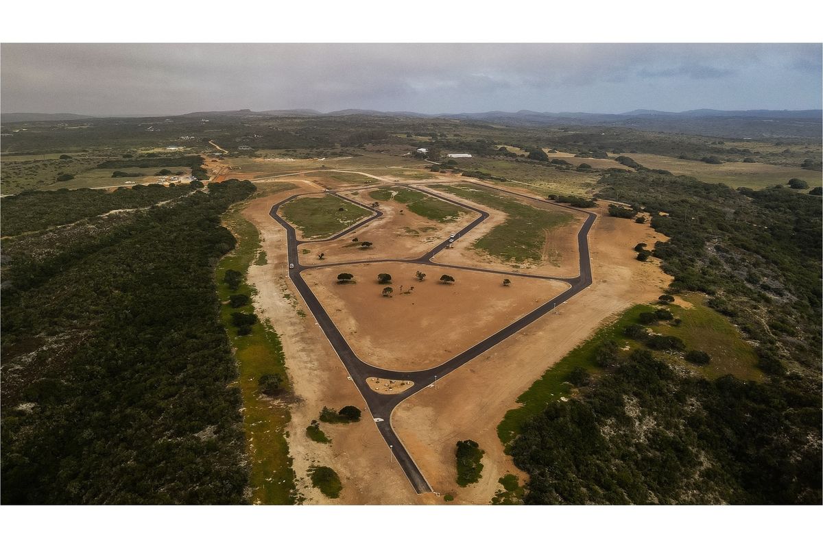 Aerial view of a residential land development featuring newly paved roads and cleared plots set within a natural landscape.