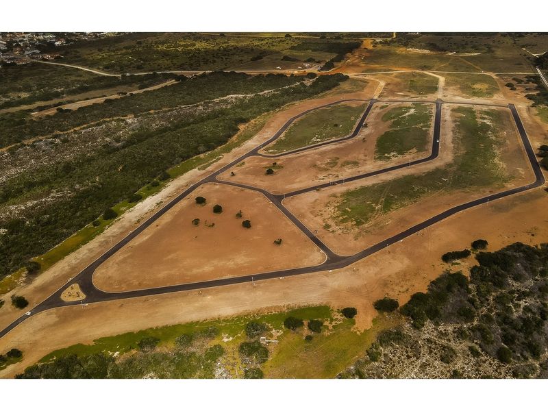 Aerial view of a residential development site featuring newly paved roads, street lighting, and cleared plots ready for construction.