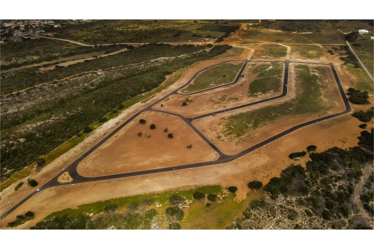 Aerial view of a residential development site featuring newly paved roads, street lighting, and cleared plots ready for construction.