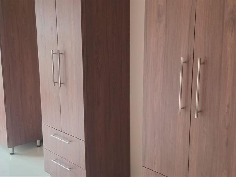 A bedroom featuring built-in wooden wardrobes with modern metal handles and tiled flooring.