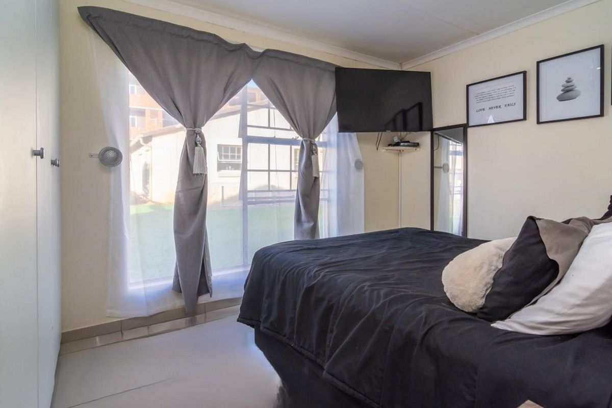 A bedroom featuring tiled flooring, built-in wardrobe storage, and a large window providing natural light and views of the exterior grounds.