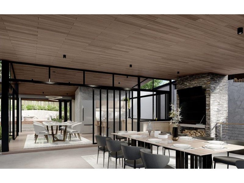 A spacious open-plan indoor-outdoor entertainment area featuring a stone fireplace, timber-clad ceiling, and seamless transition to the dining space.