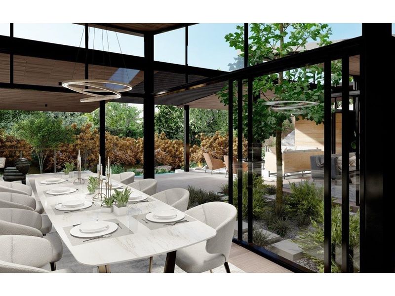 A modern open-plan dining area featuring floor-to-ceiling glass walls, sleek black structural framing, and seamless transition to an outdoor patio and garden space.