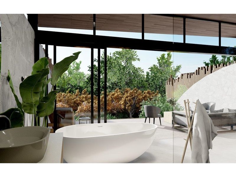 Modern bathroom featuring a freestanding bathtub and stone wall accents, seamlessly opening to a private outdoor patio area through large glass sliding doors.