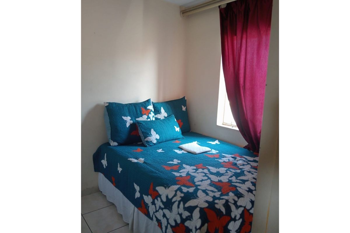 A compact bedroom featuring tiled flooring and a window with curtain track.
