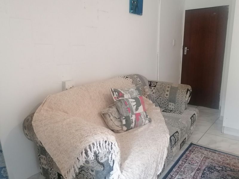 A simple living area featuring tiled flooring and a solid core interior door.