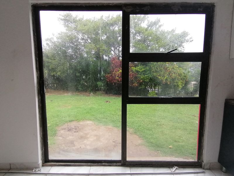 An interior view of a living space featuring a large sliding glass door with direct access to the rear garden area.