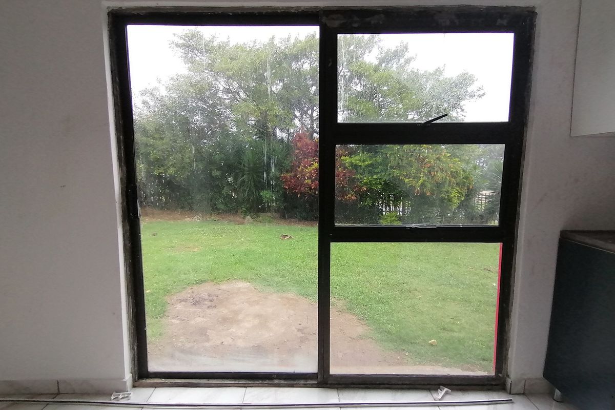 An interior view of a living space featuring a large sliding glass door with direct access to the rear garden area.