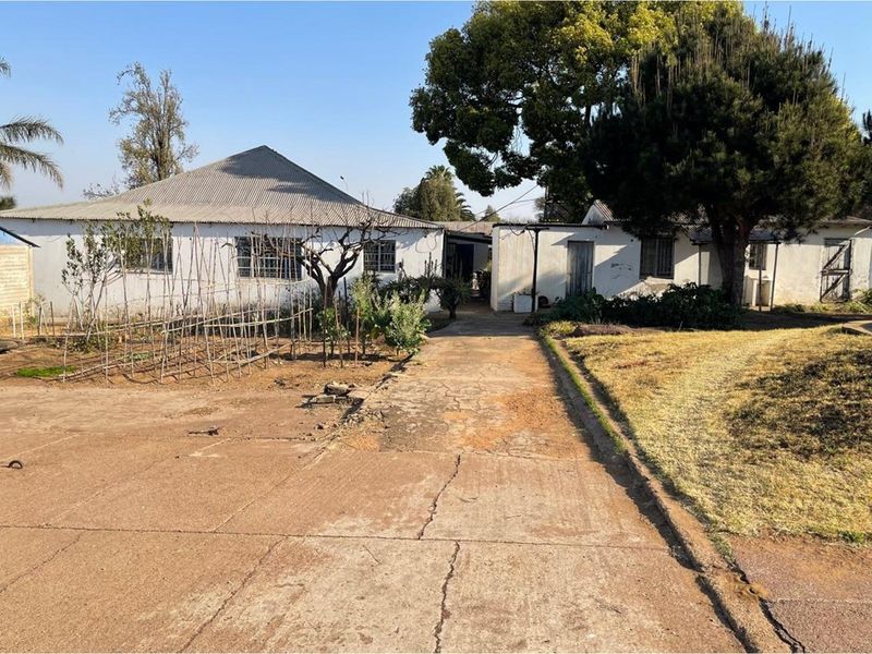 View of the residential property exterior featuring a concrete driveway leading to the main dwelling and surrounding garden area.