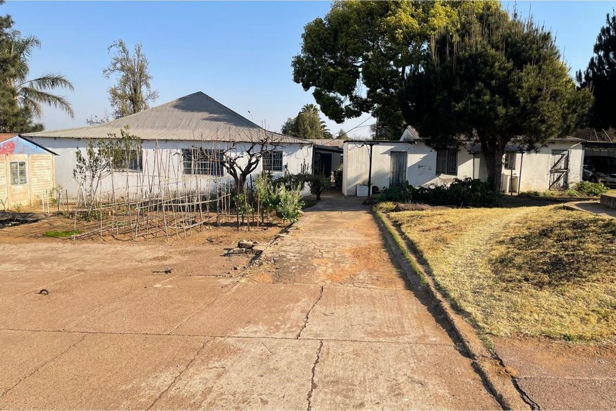 View of the residential property exterior featuring a concrete driveway leading to the main dwelling and surrounding garden area.