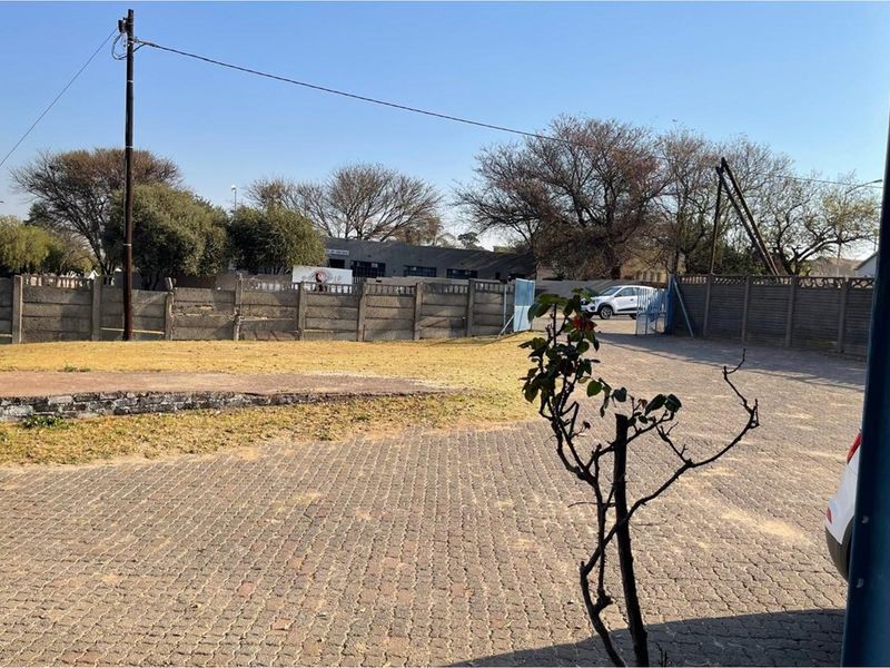A view of the residential vacant land featuring paved driveway access, precast concrete boundary walls, and established trees in the background.