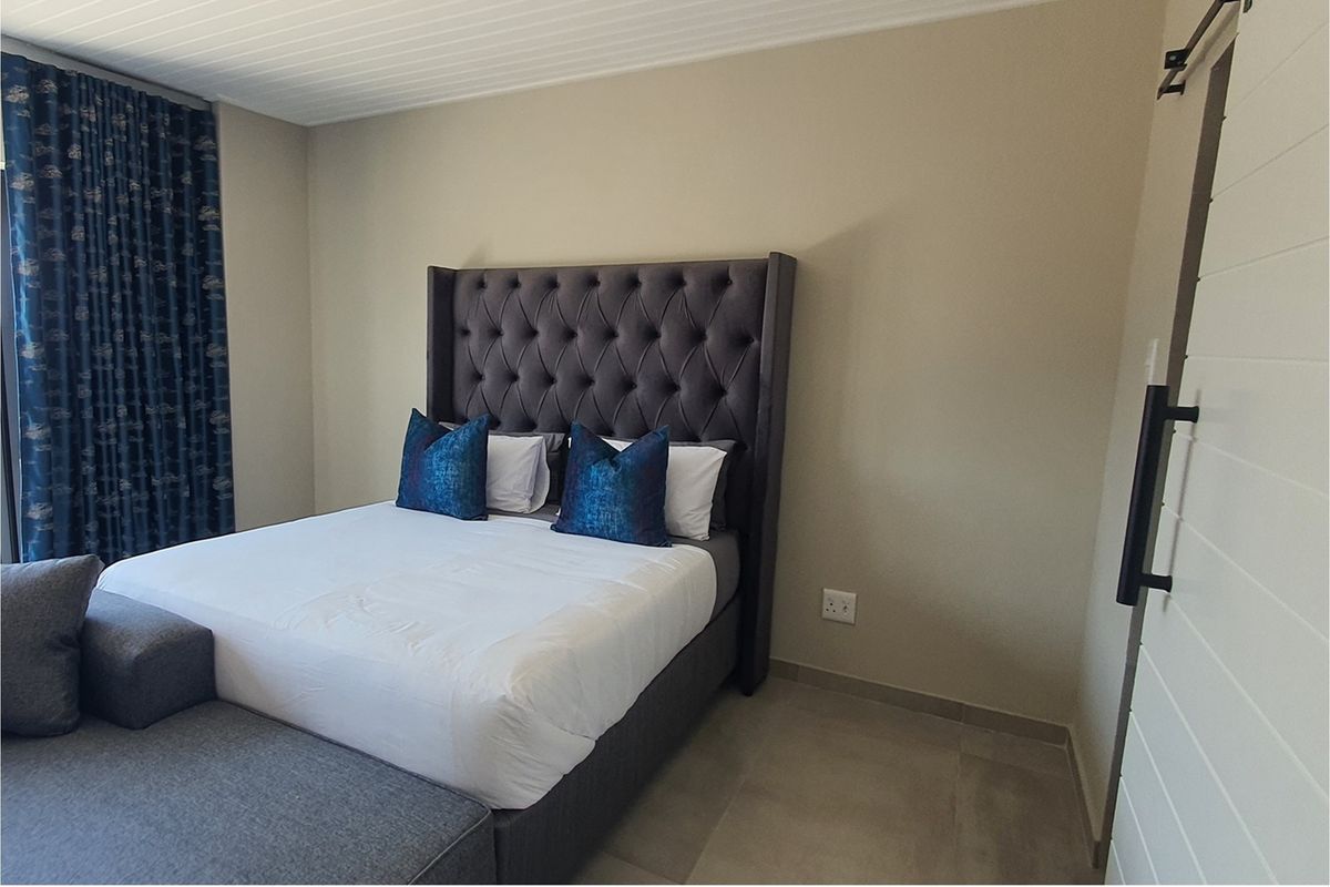 A well-maintained bedroom featuring neutral wall tones, tiled flooring, and a sliding barn-style door.