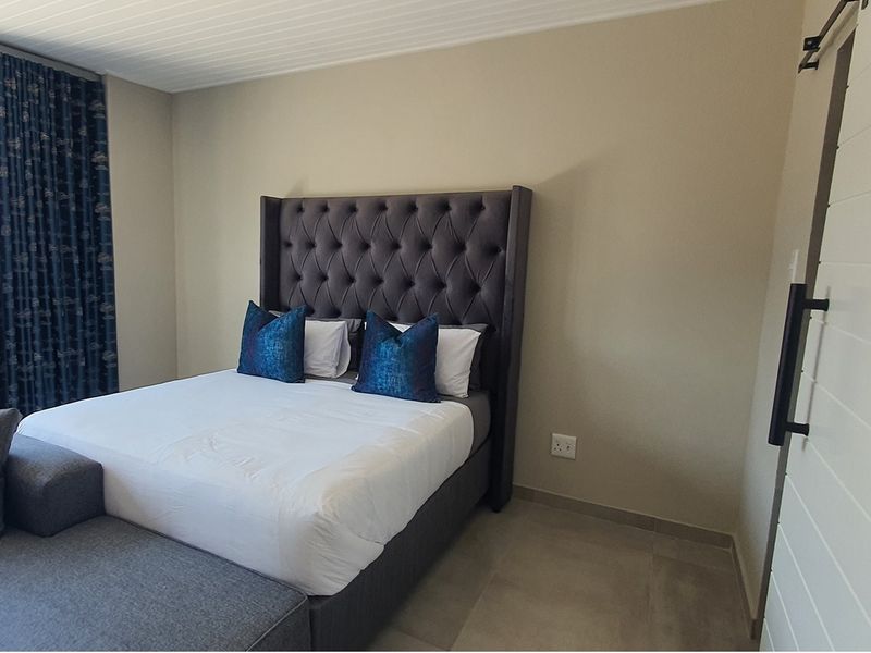 A well-maintained bedroom featuring neutral wall tones, tiled flooring, and a sliding barn-style door.