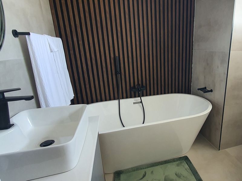 Modern bathroom featuring a freestanding bathtub, matte black fixtures, and a decorative timber slat feature wall.