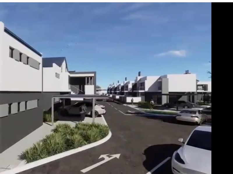 A digital architectural rendering of a modern apartment complex featuring paved driveways, covered parking bays, and contemporary building facades.