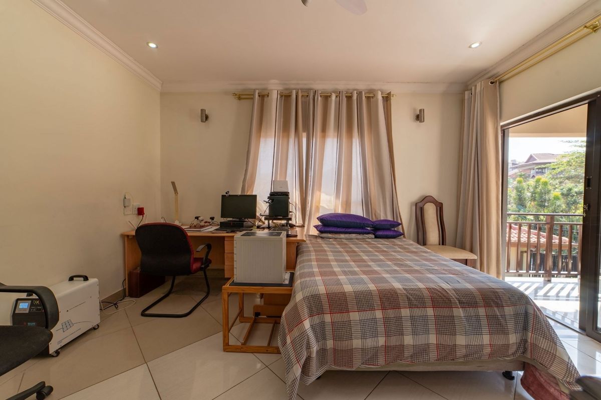 A bedroom featuring tiled flooring, recessed ceiling lighting, and sliding glass doors providing access to an outdoor balcony.