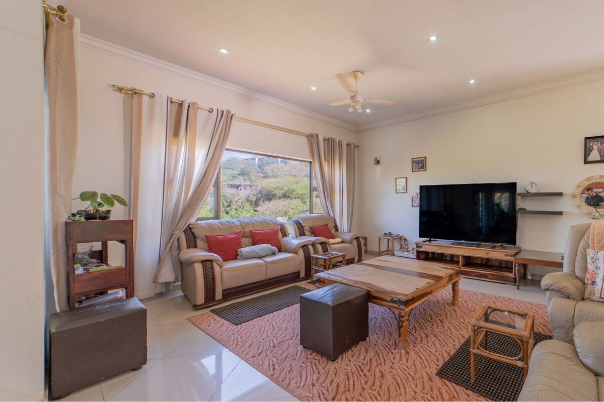 Spacious living room featuring large windows with natural light, tiled flooring, recessed ceiling lighting, and a ceiling fan.