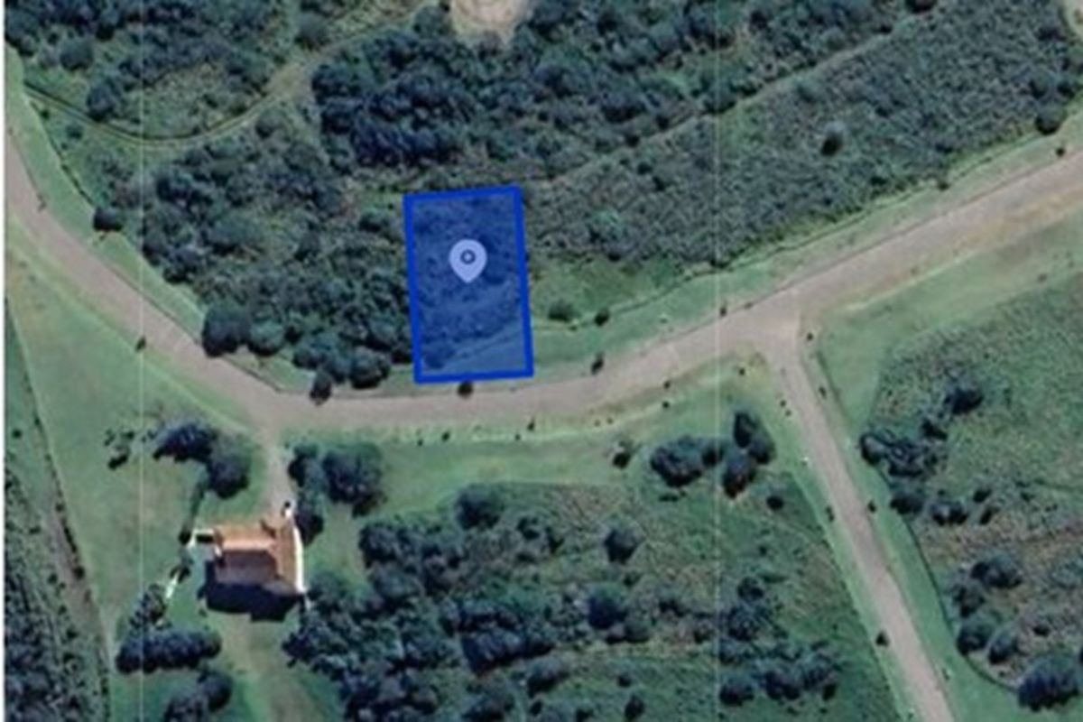 An aerial view of a vacant residential plot highlighted in blue, situated within a landscaped estate environment with surrounding vegetation and access roads.