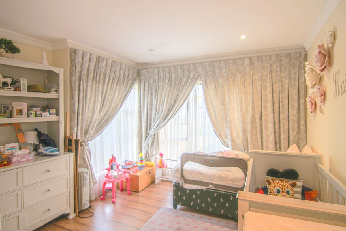 A well-maintained bedroom featuring wood-look flooring, recessed ceiling lighting, and floor-to-ceiling curtains covering the windows.