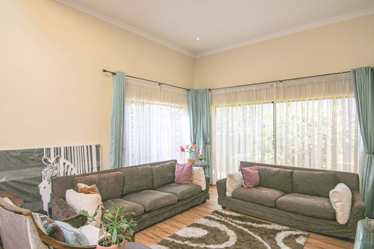 Spacious living room featuring high ceilings, large windows with natural light, and wood-look flooring, creating a bright and comfortable atmosphere.