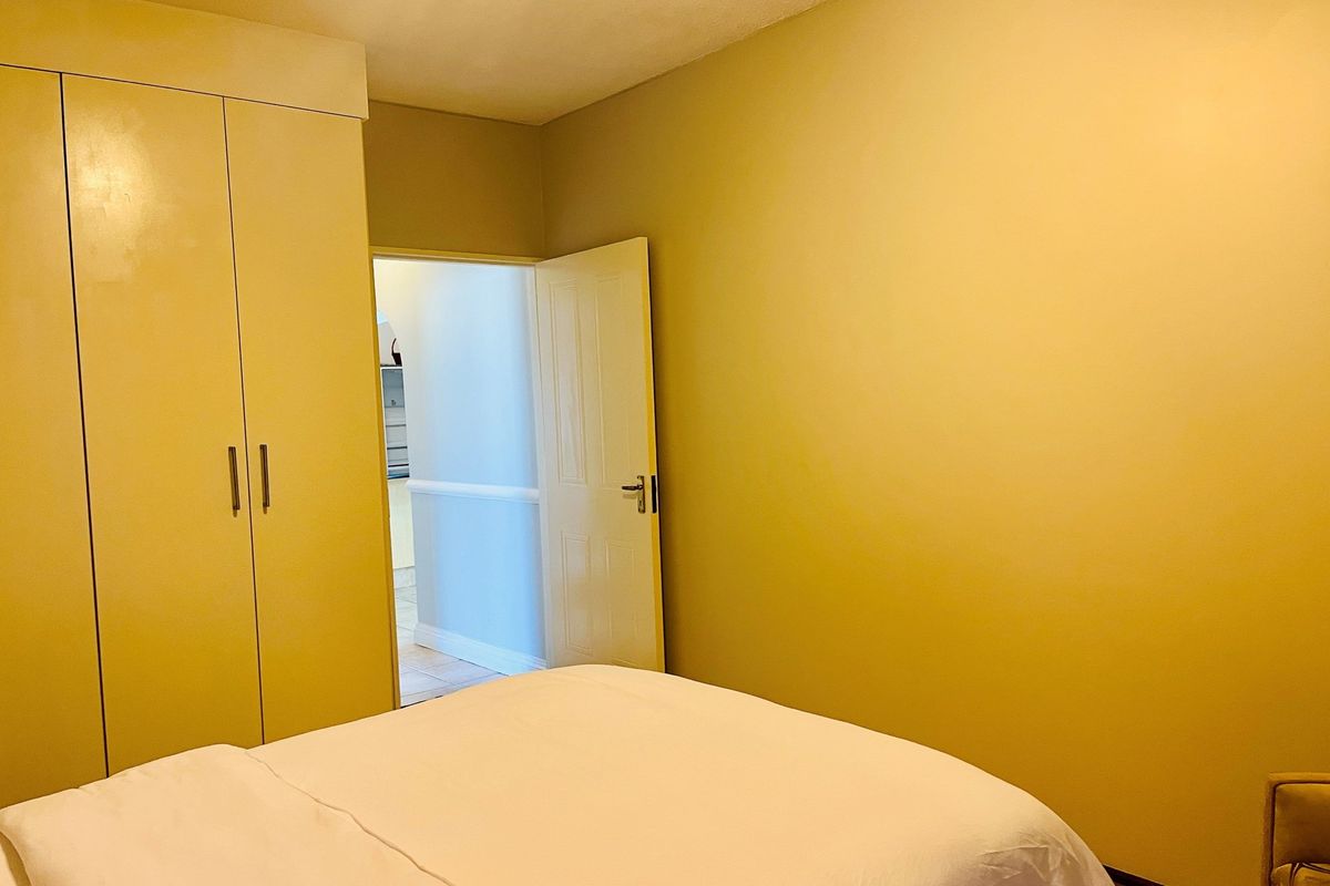 A bedroom featuring built-in floor-to-ceiling wardrobes and a doorway leading to an adjacent hallway.