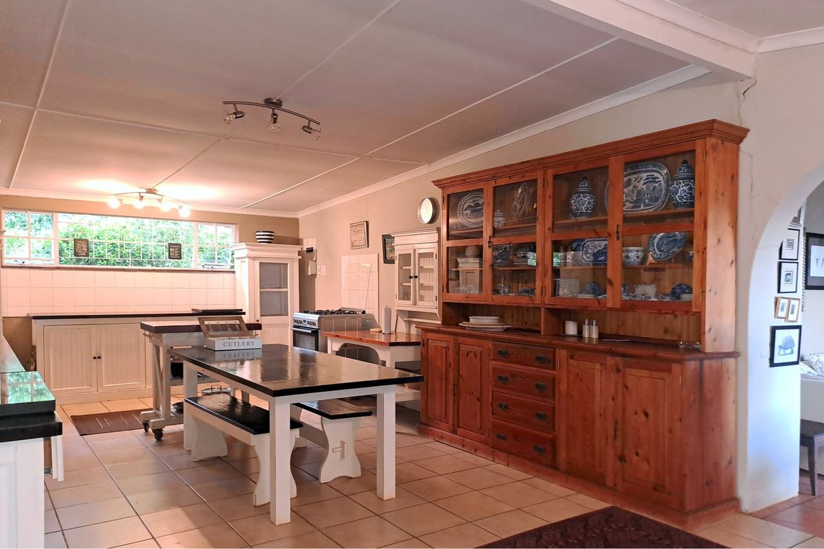 Spacious farmhouse kitchen featuring tiled flooring, built-in cabinetry, and a gas stove, offering a warm and functional cooking and dining environment.