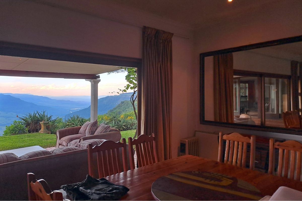 Living room featuring large sliding doors that open onto a covered patio with expansive mountain and valley views.