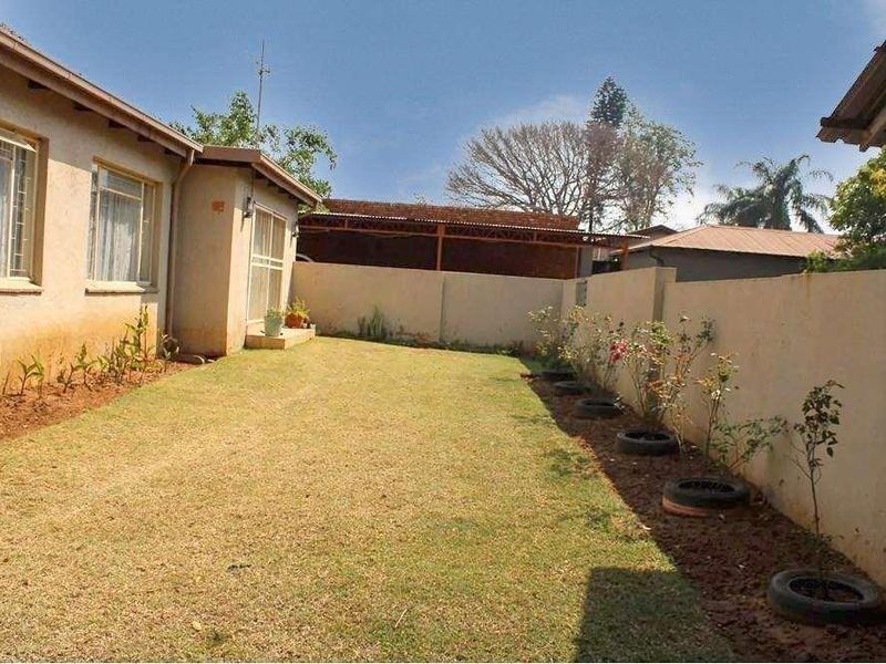 A rear garden area featuring a lawn, boundary wall, and access to the house via a sliding door.