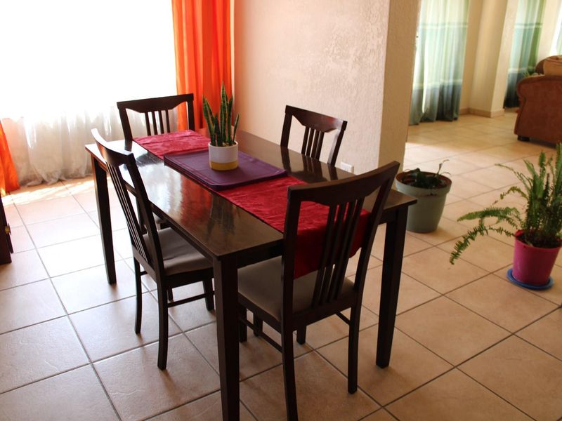 A dining area featuring neutral ceramic floor tiles and an open-plan layout connecting to the adjacent living space.