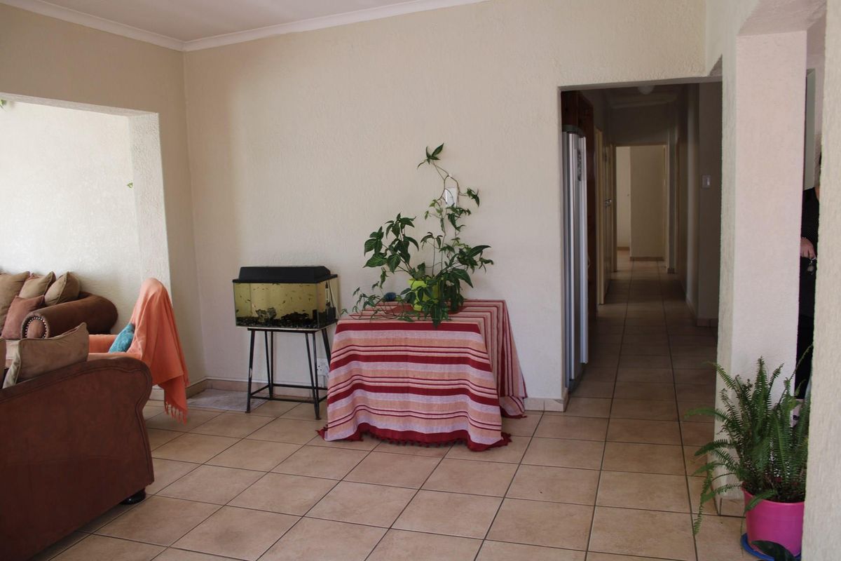 A living area featuring neutral wall finishes, ceramic floor tiles, and an open archway leading to a hallway.