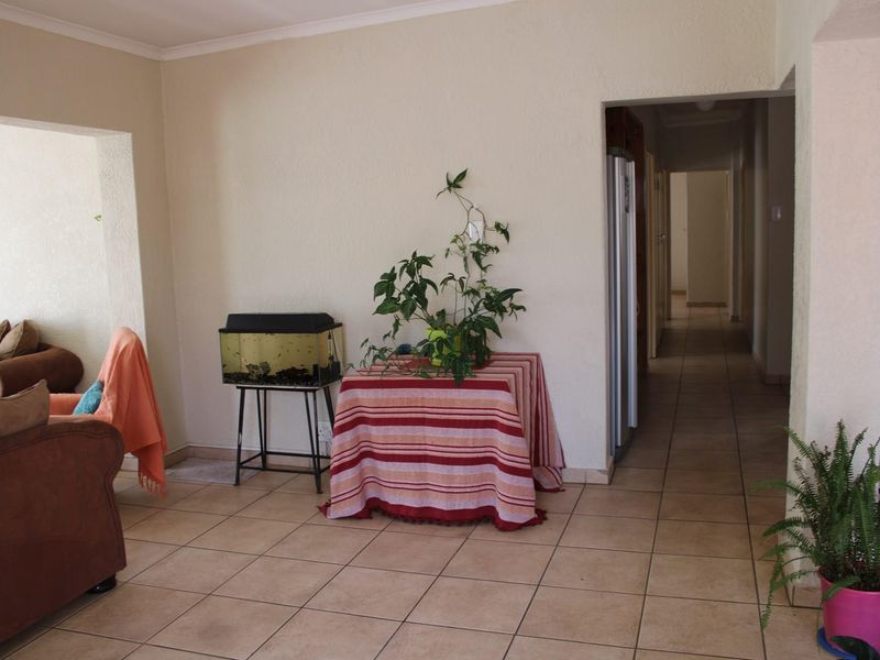 A living area featuring neutral wall finishes, ceramic floor tiles, and an open archway leading to a hallway.