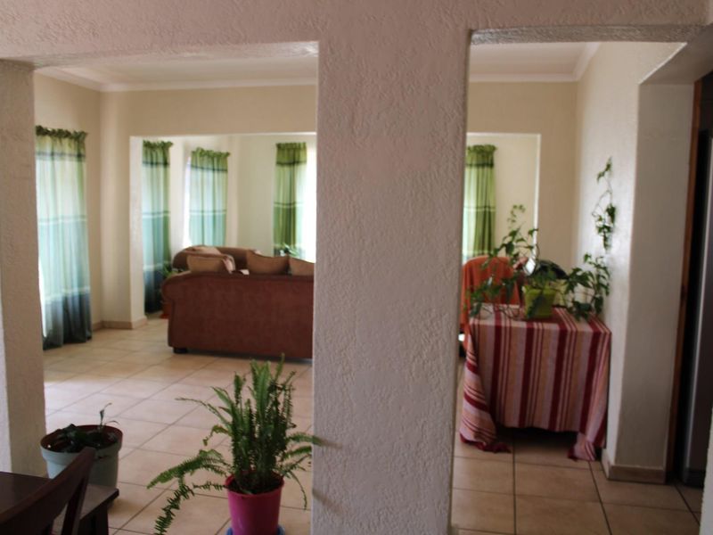 Open plan living area featuring ceramic floor tiles, structural columns, and coved cornicing, providing a connected layout between living and dining spaces.