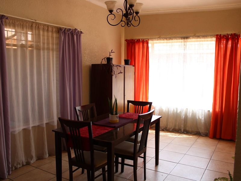 A dining room featuring tiled flooring, a central chandelier, and large windows that provide ample natural light.