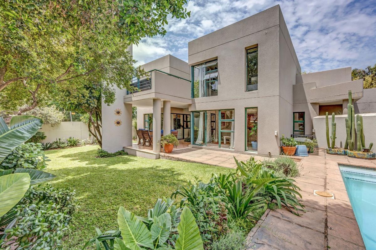 Rear view of a modern townhouse featuring a covered patio, landscaped garden, and a private swimming pool.