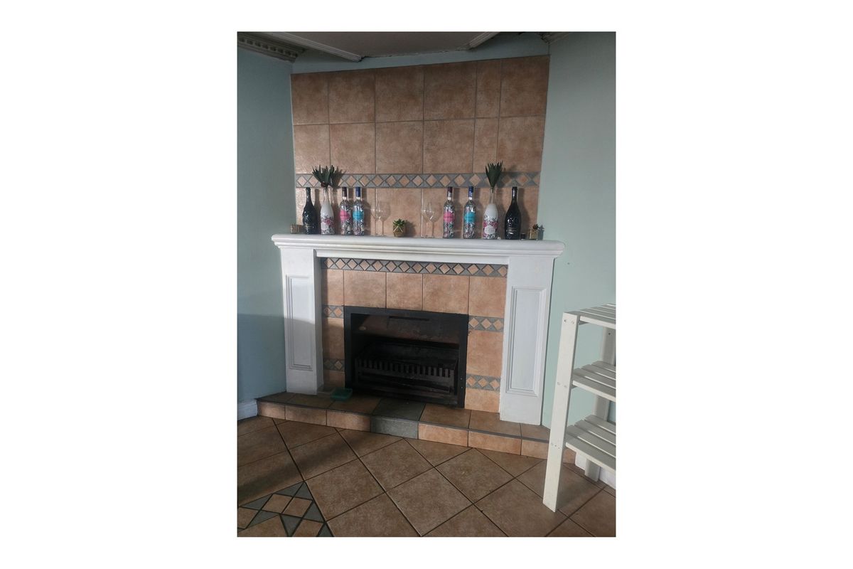 A living room featuring a traditional fireplace with a tiled surround and hearth, complemented by ceramic floor tiling.