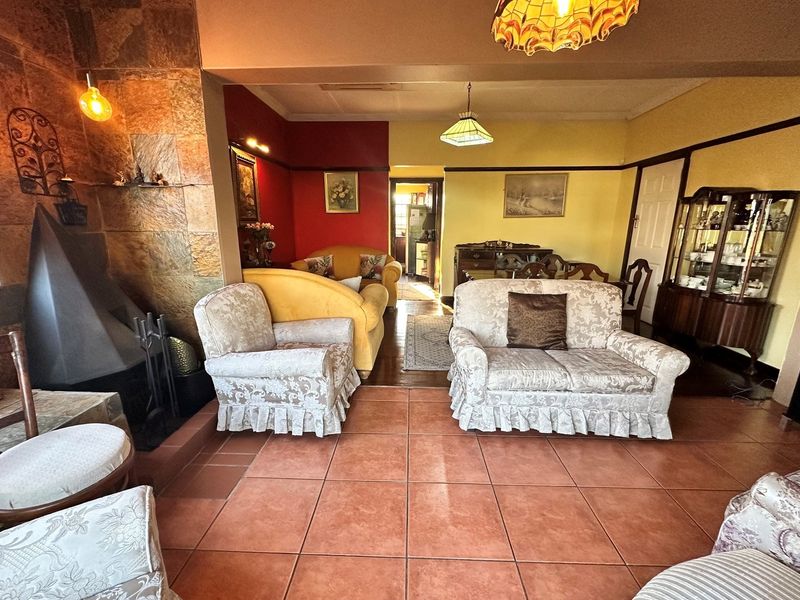 Spacious living area featuring a prominent stone-clad fireplace, tiled flooring, and a warm, traditional interior layout.