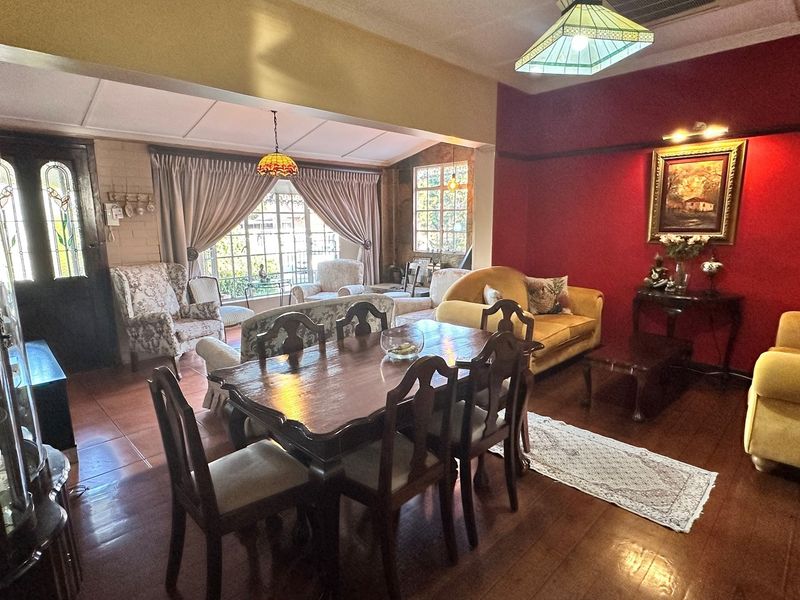 Spacious open-plan living and dining area featuring tiled flooring, decorative lighting, and large windows allowing for natural light.