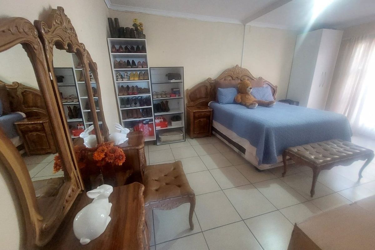A spacious bedroom featuring tiled flooring and built-in wardrobe storage, offering a functional layout with ample room for bedroom furniture.