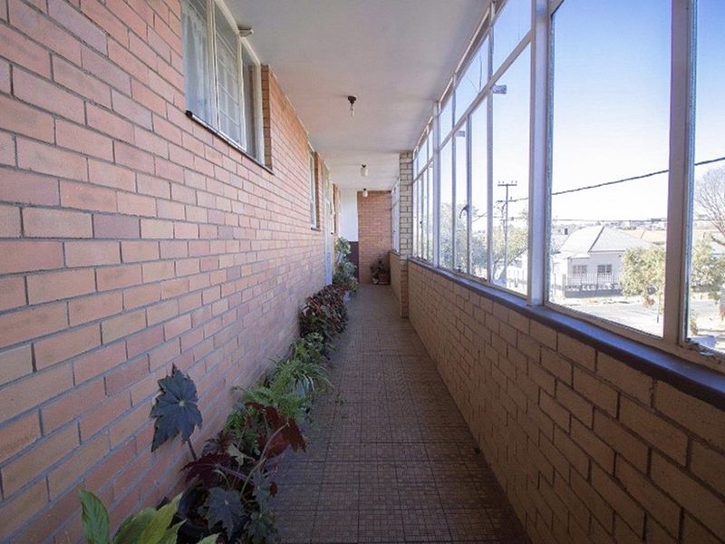 An enclosed balcony featuring brick walls, tiled flooring, and large windows providing natural light and neighborhood views.