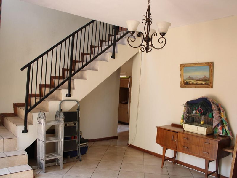 Entrance area featuring a tiled staircase with a metal balustrade and a decorative chandelier, leading to an adjacent living space.