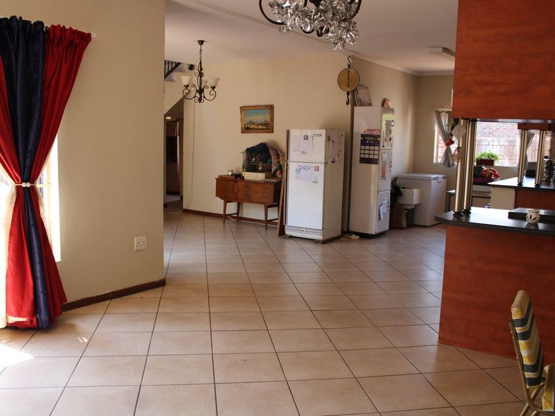 Open plan living and kitchen area featuring tiled flooring, built-in cabinetry, and a breakfast bar, offering a functional layout for daily living.