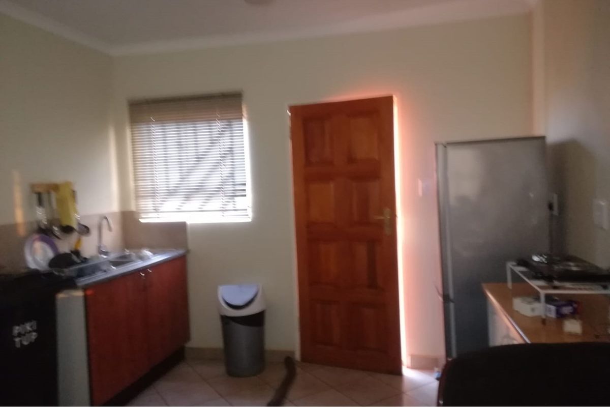 A functional kitchen area featuring wooden cabinetry, a stainless steel sink, and a window with fitted blinds.