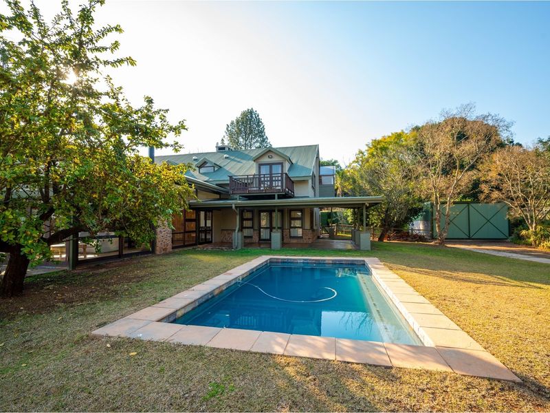 Rear view of the property featuring a swimming pool, covered patio area, and a multi-level house with a balcony.