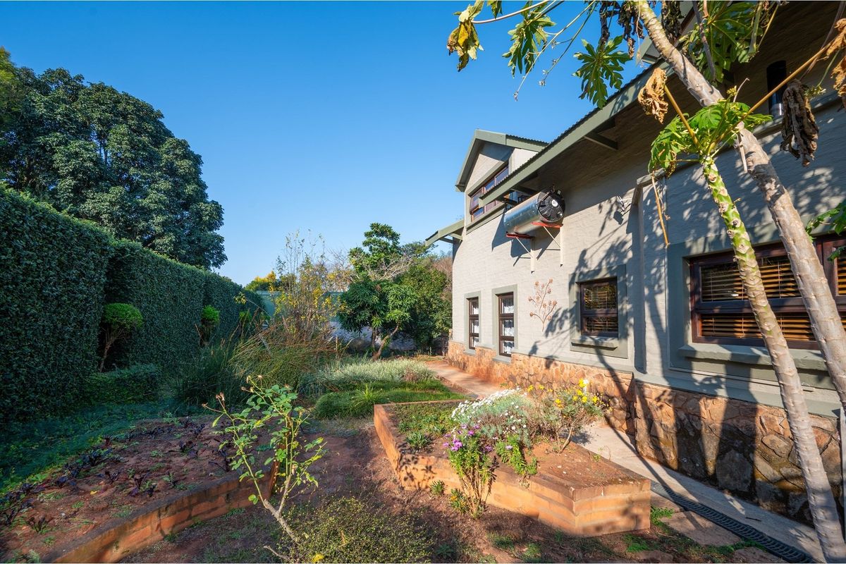 Rear exterior view of the house featuring a landscaped garden with brick-edged planter beds and a wall-mounted solar water heater.