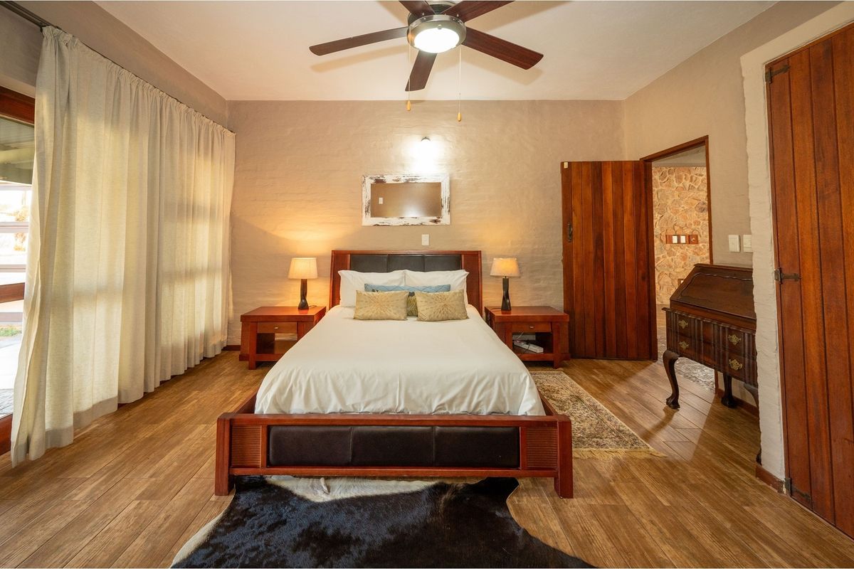 A well-maintained bedroom featuring wood-look flooring, a ceiling fan, and a solid timber door leading to an adjacent space.