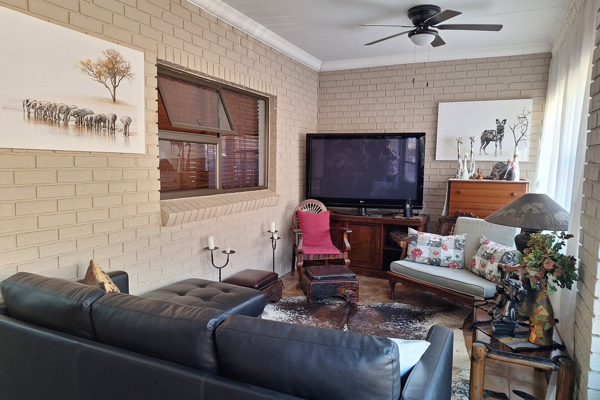 A cozy living room featuring exposed brick walls, tiled flooring, and a ceiling fan, creating a warm and inviting atmosphere.