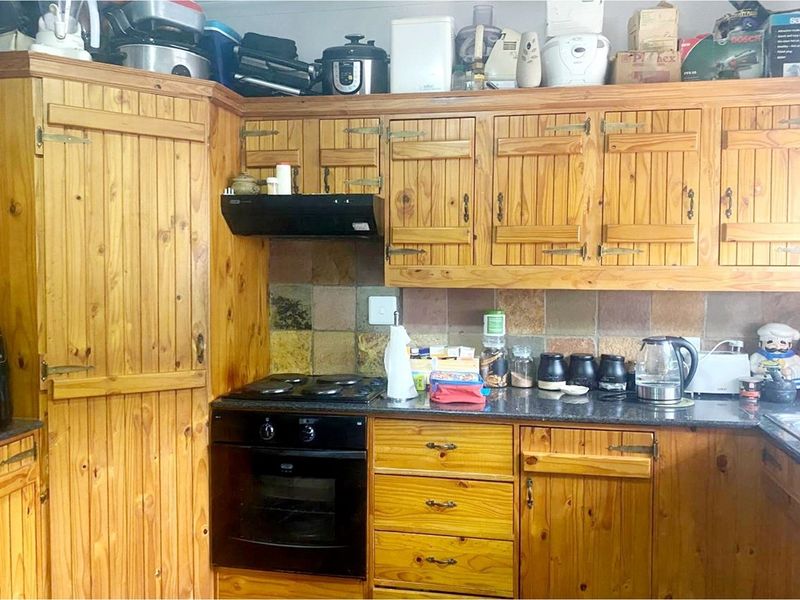A functional kitchen featuring traditional wooden cabinetry, stone countertops, a built-in oven, and a tiled backsplash.