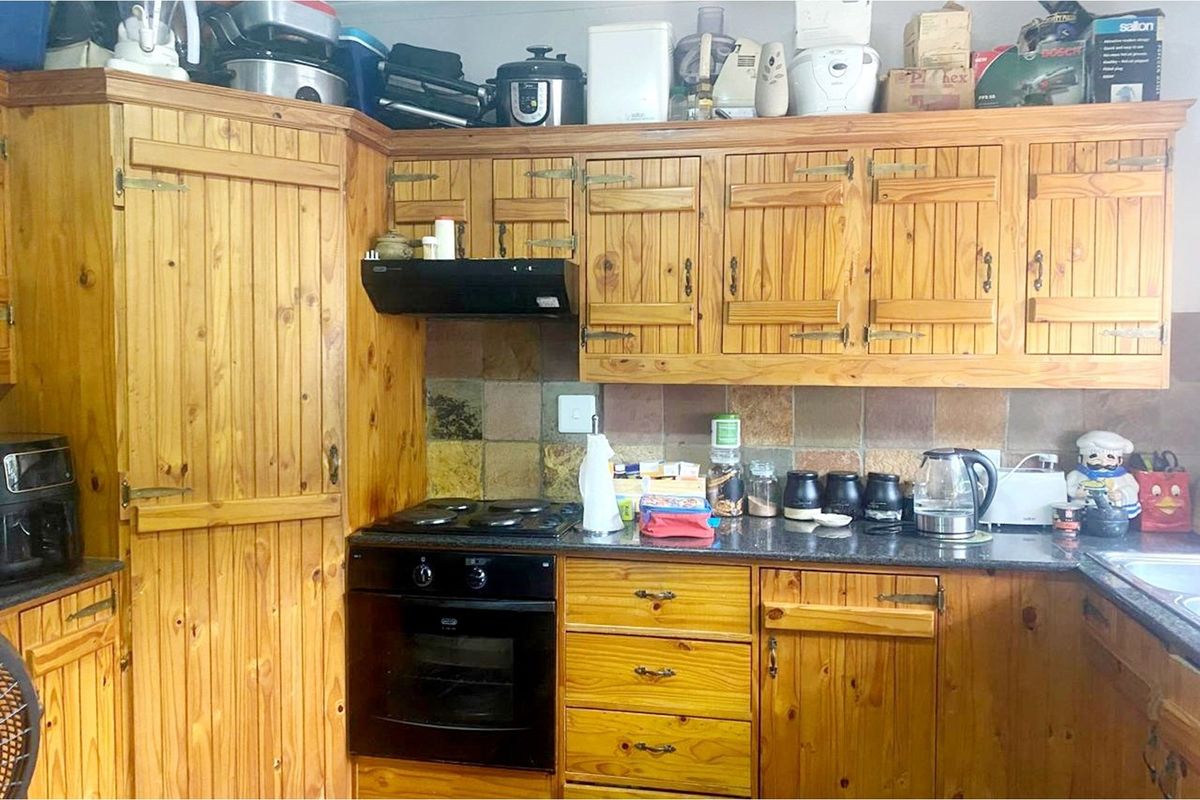 A functional kitchen featuring traditional wooden cabinetry, stone countertops, a built-in oven, and a tiled backsplash.
