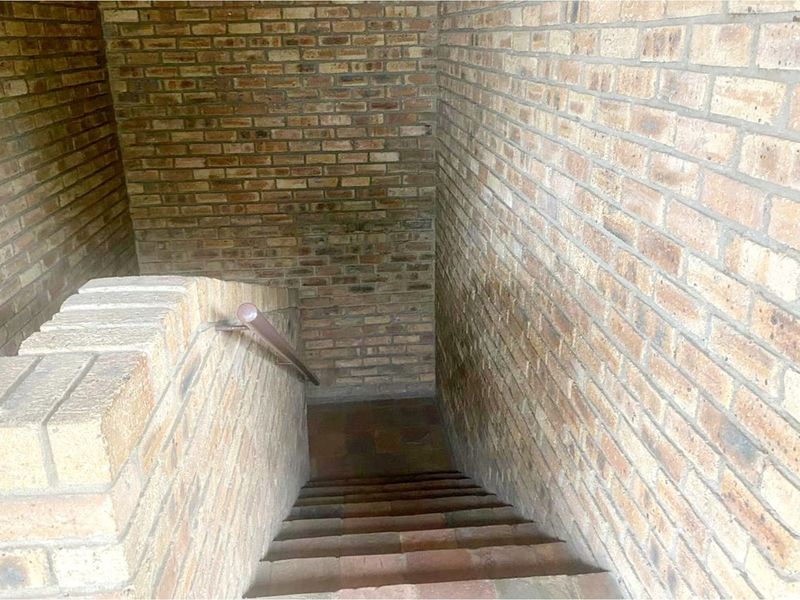 A functional staircase featuring exposed brick walls and a simple handrail, providing access between levels.