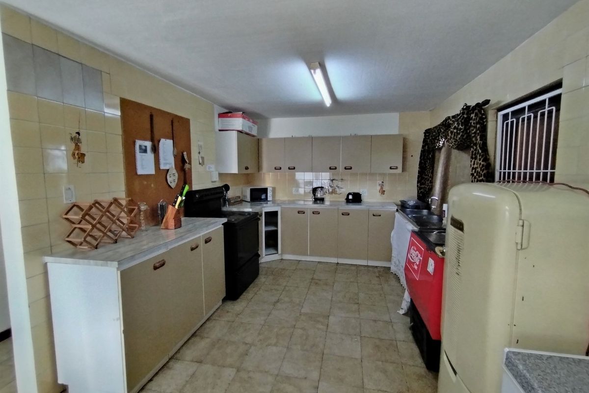 A functional kitchen featuring dated cabinetry, tiled flooring, and wall-mounted storage, offering a practical layout with potential for modernization.
